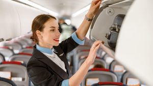 стюардесса смотрит багажный отсек чемодан